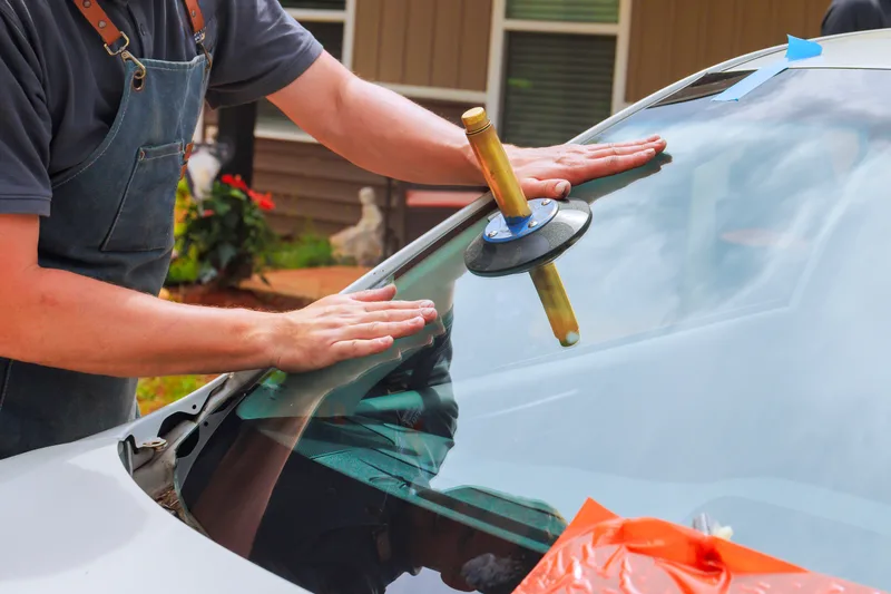 Mobile glass technician working at a vehicle outside a customer’s home