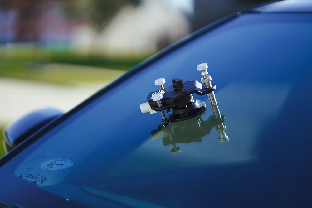 Close-up of a professional windshield chip repair bridge attached to vehicle glass